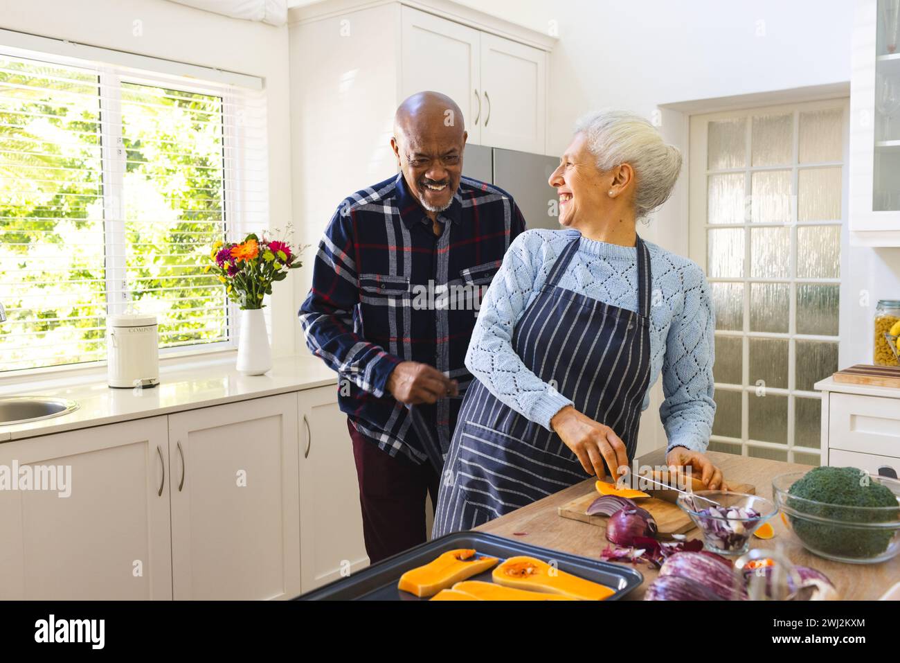Felice coppia di anziani che trita verdure in cucina Foto Stock