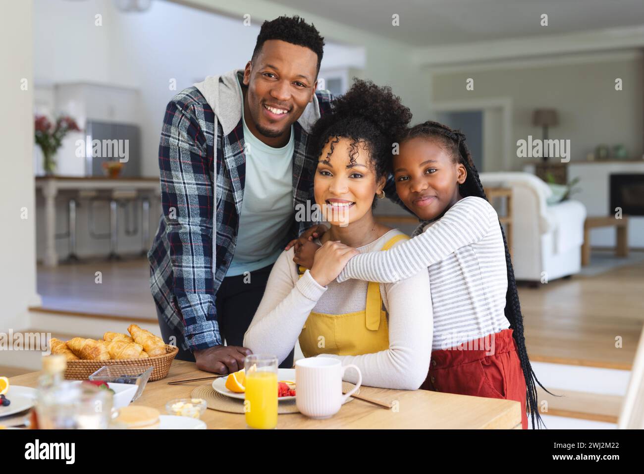 Ritratto della felice famiglia afroamericana che abbraccia al tavolo nella sala da pranzo di casa, spazio fotocopie Foto Stock