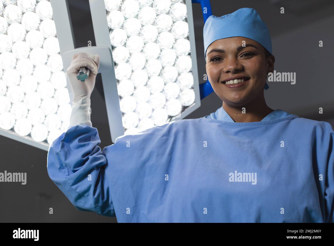 Ritratto di una donna chirurgo birazziale felice che indossa un abito chirurgico in sala operatoria Foto Stock