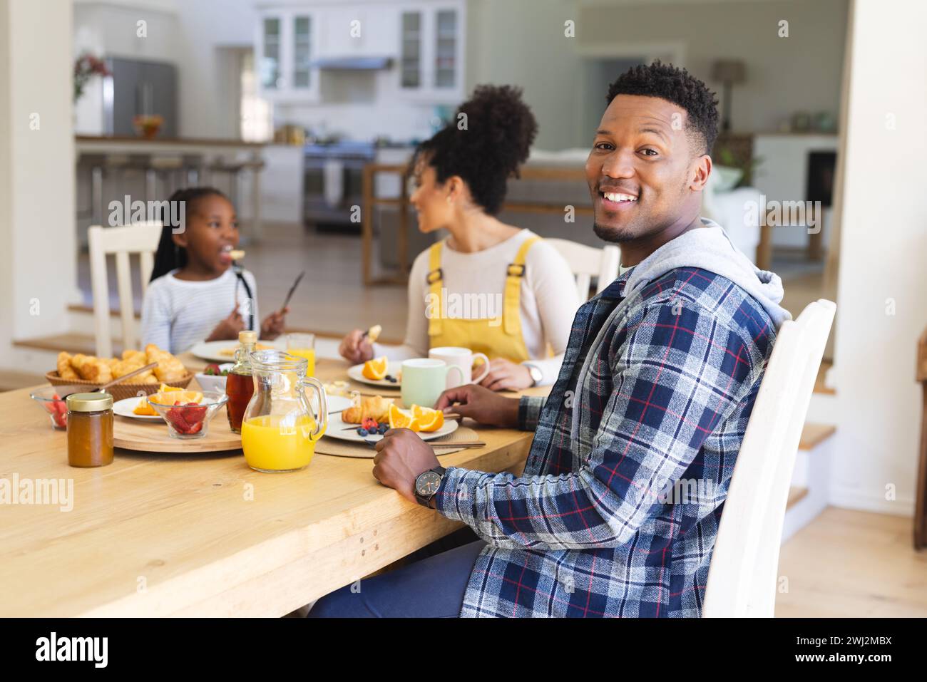 Felice uomo afroamericano seduto a tavola, facendo uno spuntino con la famiglia a casa, copia spazio Foto Stock