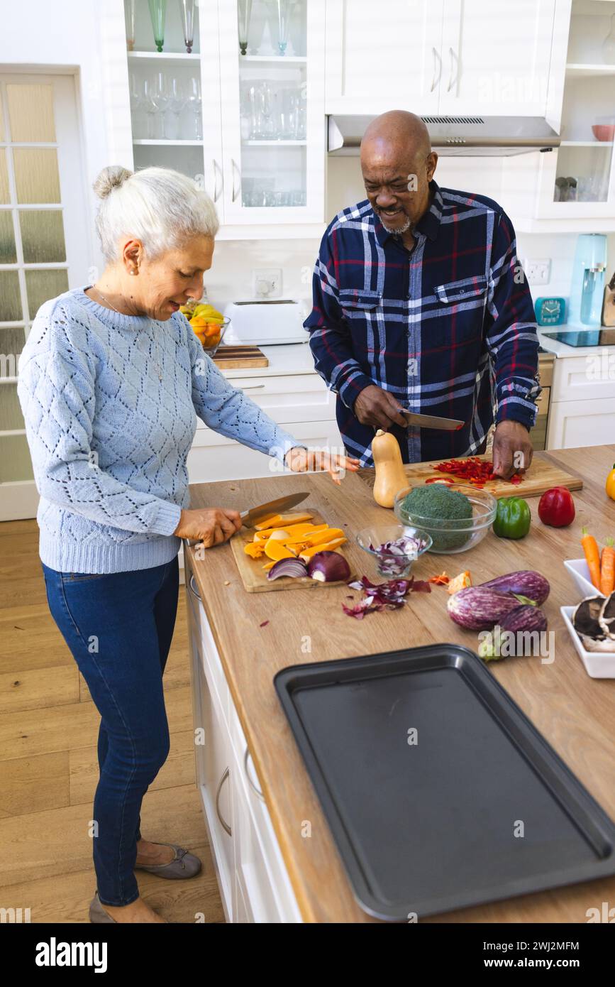 Diverse coppie di anziani tagliano verdure in cucina Foto Stock