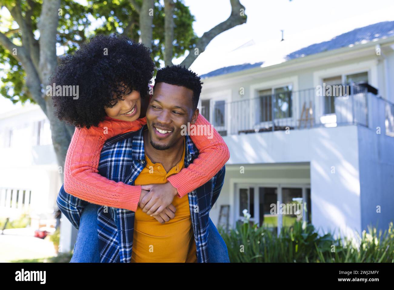 Felice coppia afroamericana che cavalca il piggyback nel giardino soleggiato, spazio fotocopie Foto Stock