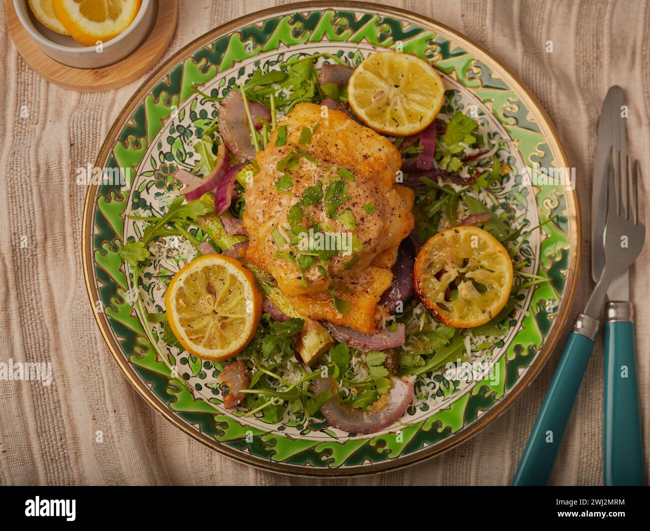 Filetti di merluzzo al forno con condimento ed erbe aromatiche su un'insalata di rucola. Foto Stock