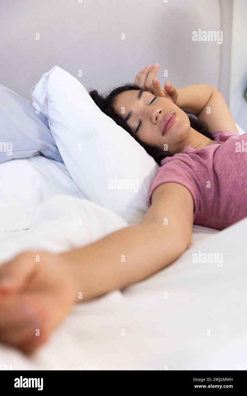 Donna birazziale che dorme sdraiata a letto in una casa soleggiata Foto Stock