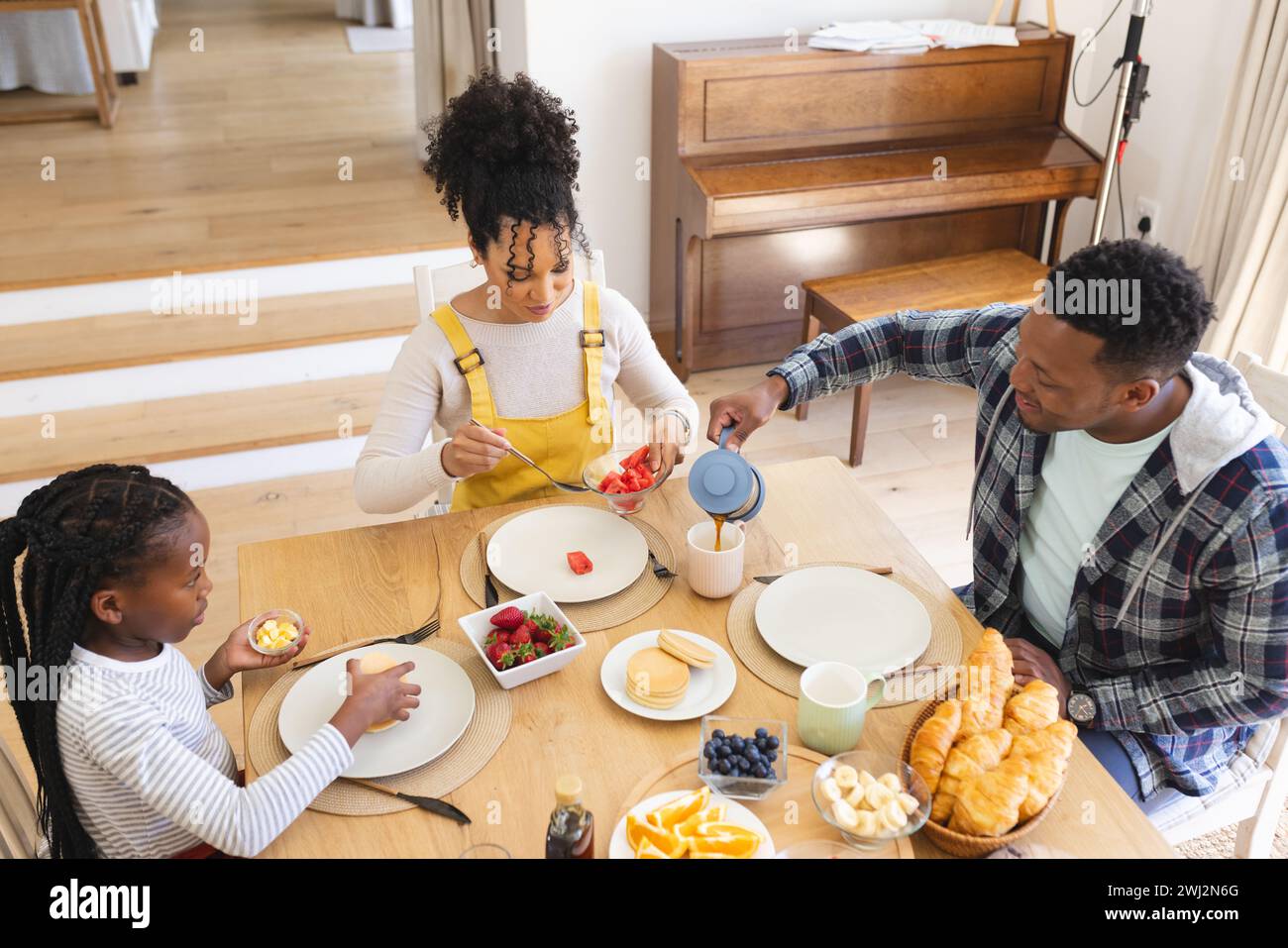 Una famiglia afroamericana felice con uno spuntino di frutta fresca nella sala da pranzo di casa, spazio per fotocopie Foto Stock