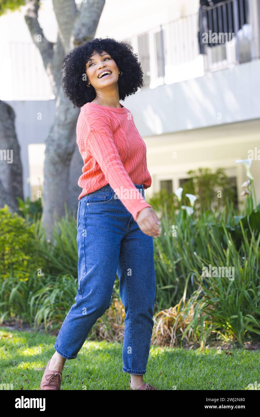 Felice donna afroamericana che cammina nel giardino soleggiato, copia spazio Foto Stock