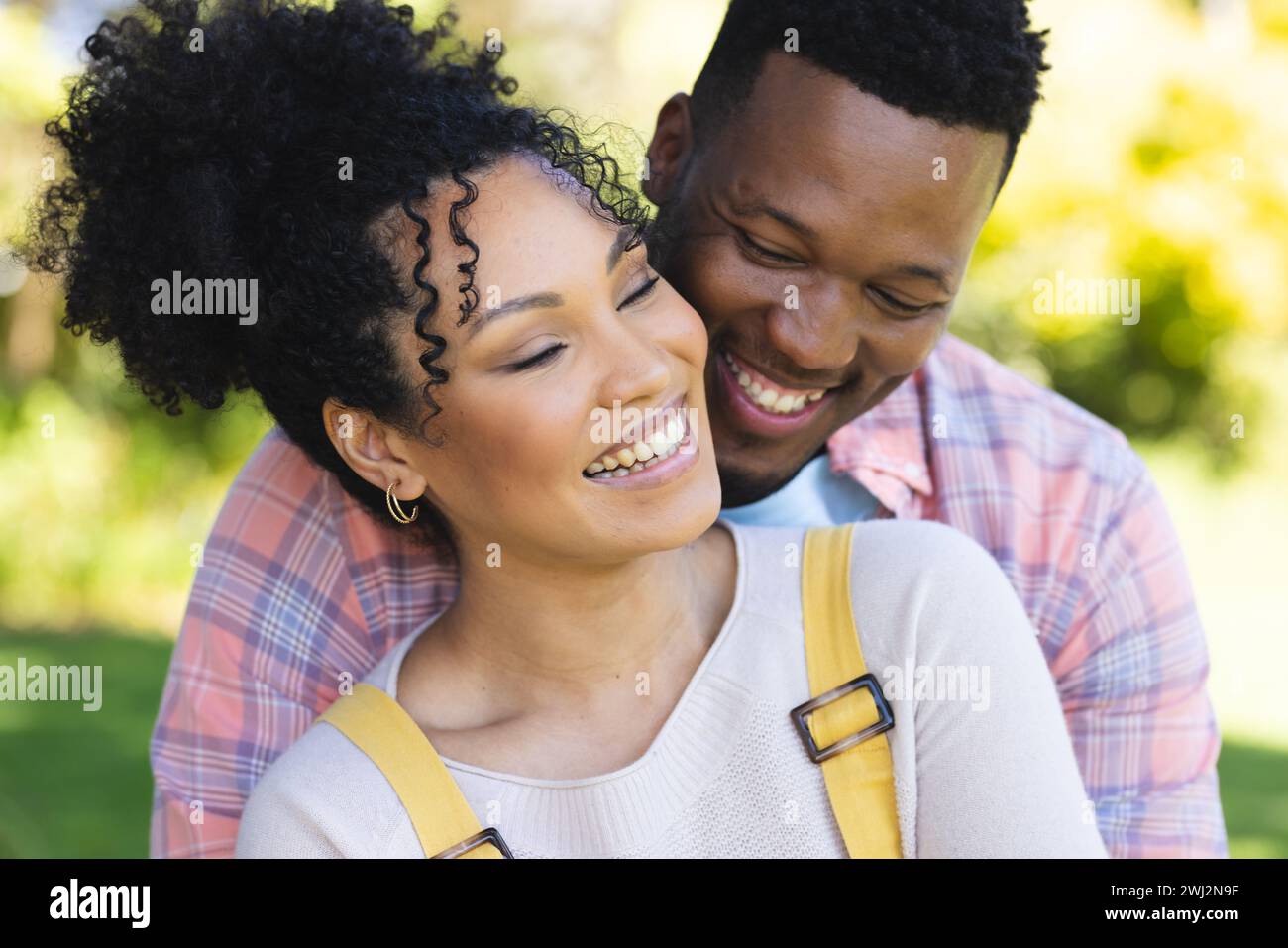Felice coppia afroamericana che abbraccia nel giardino soleggiato, spazio fotocopie Foto Stock