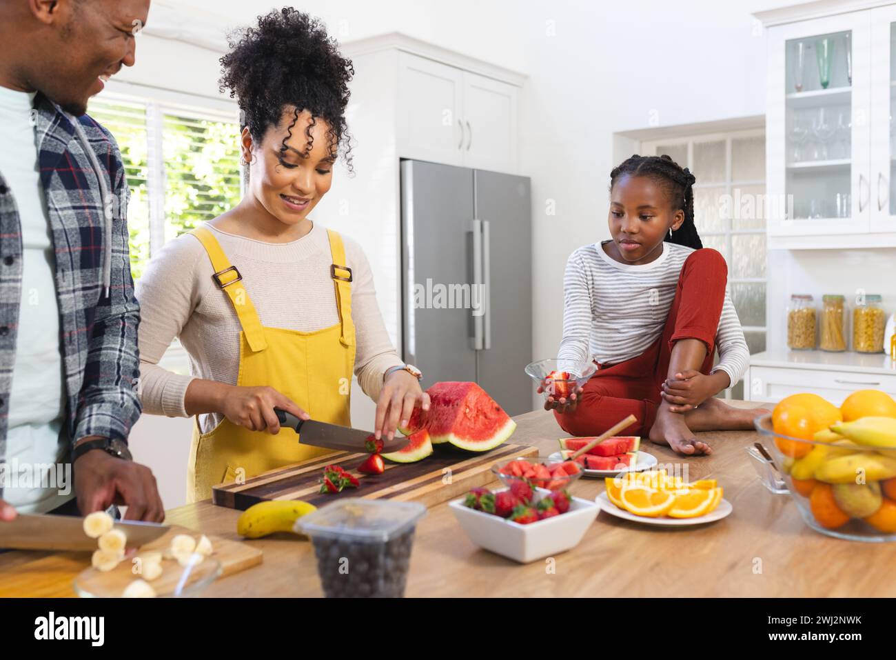 Famiglia afroamericana felice che prepara uno spuntino fresco dalla frutta in cucina a casa, copia spazio Foto Stock