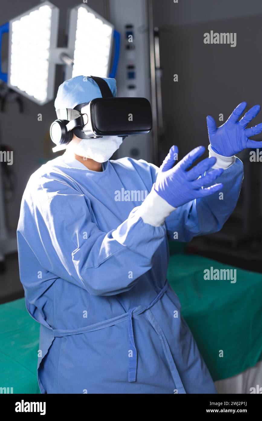 Chirurgo birazziale femminile che indossa un abito chirurgico con visore vr in sala operatoria Foto Stock