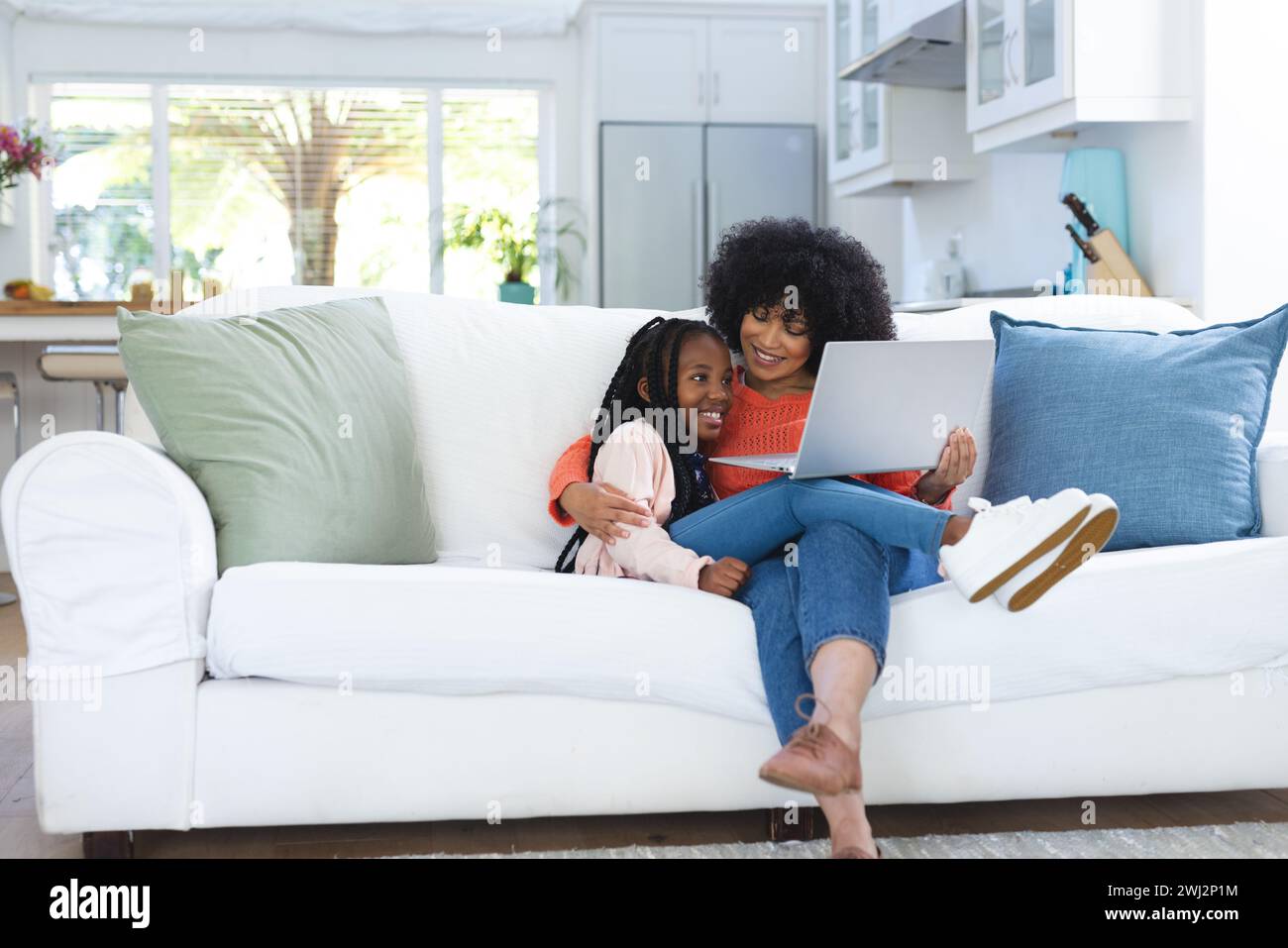 Felice madre e figlia afroamericana che abbracciano sul divano e usano un tablet a casa, copiano spazio Foto Stock