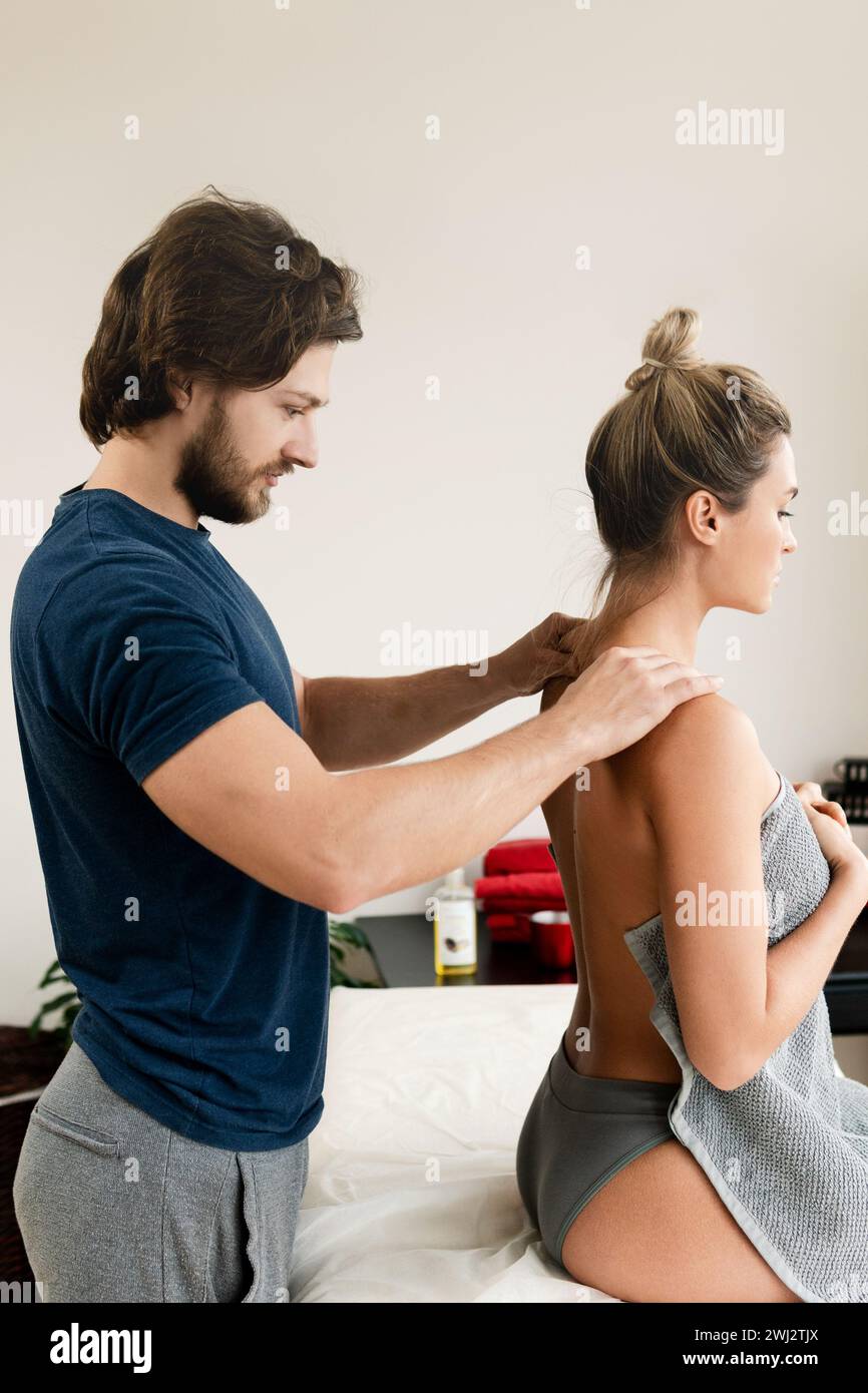 Massaggiatore che fa un massaggio alla schiena per il suo cliente Foto Stock