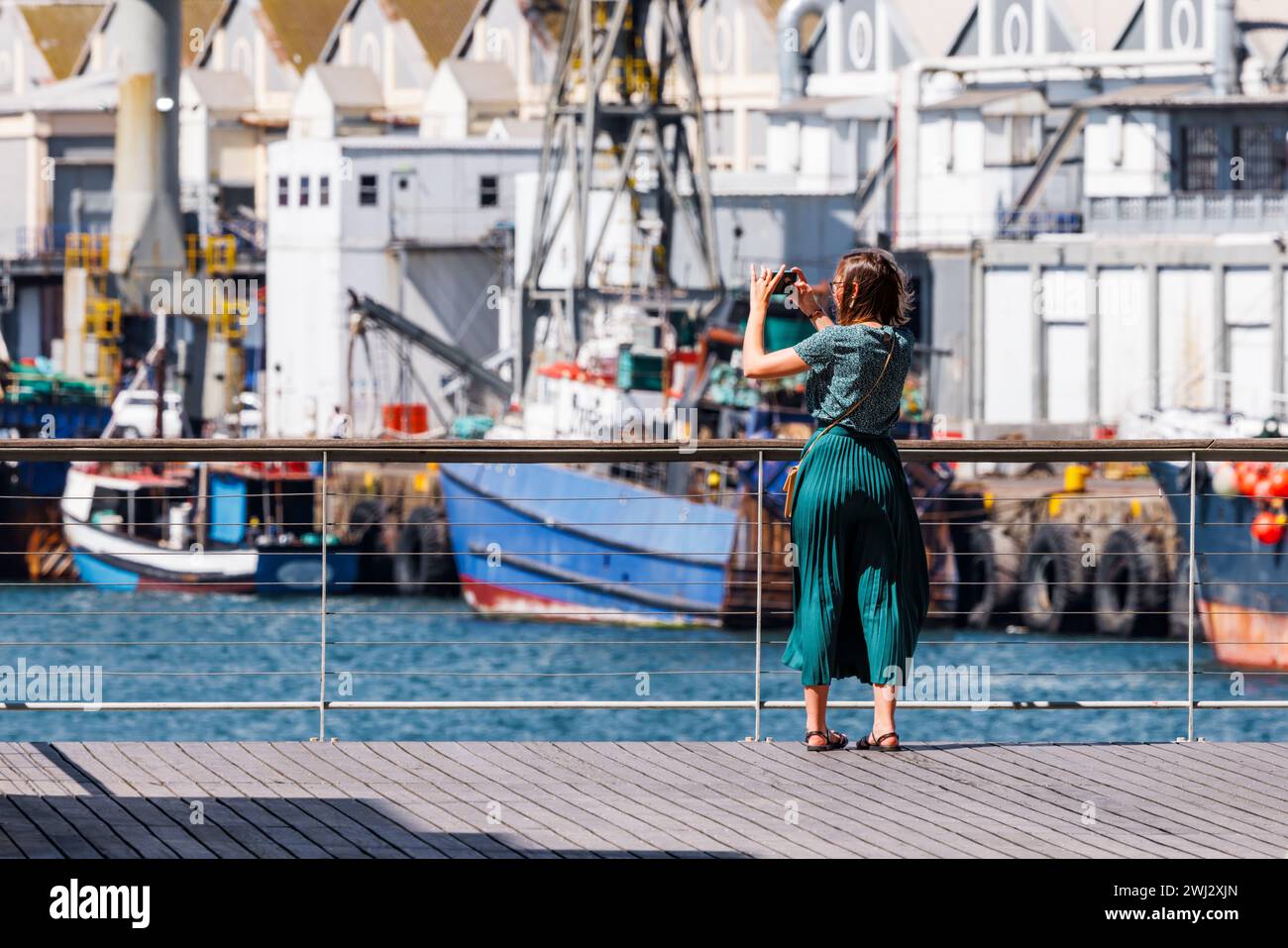 Un viaggiatore cattura la vivace attività di un porto vivace, immortalando l'essenza di una città marinara nel bagliore di una giornata luminosa e soleggiata. Foto Stock