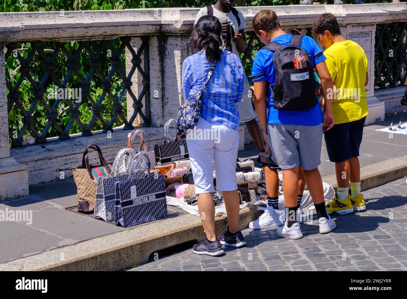 Roma, IT - 11 agosto 2023: Persone che guardano borse couterfeit vendute da un venditore ambulante Foto Stock