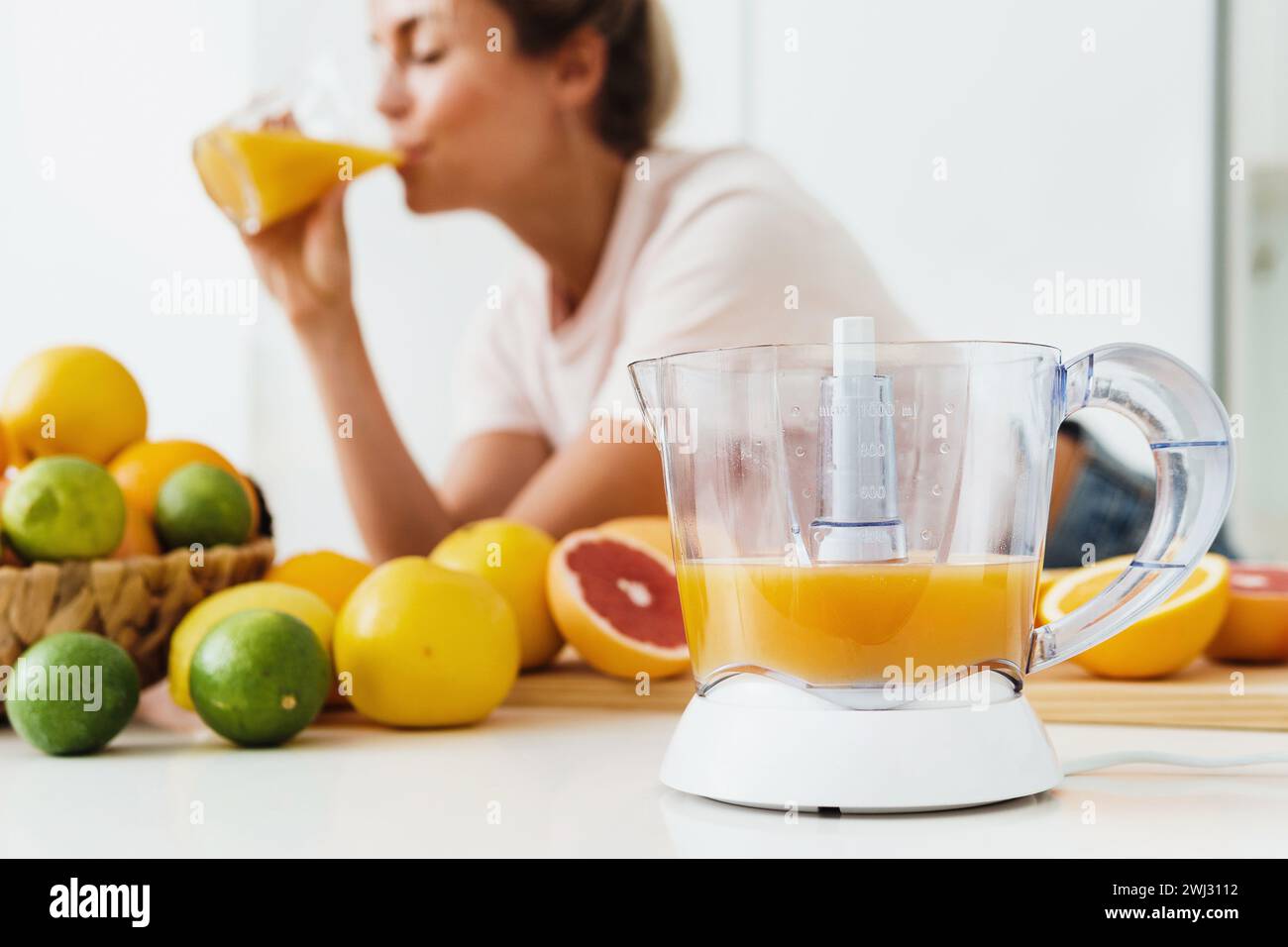 Spremiagrumi e donna che beve succo d'arancia appena spremuto in casa Foto Stock