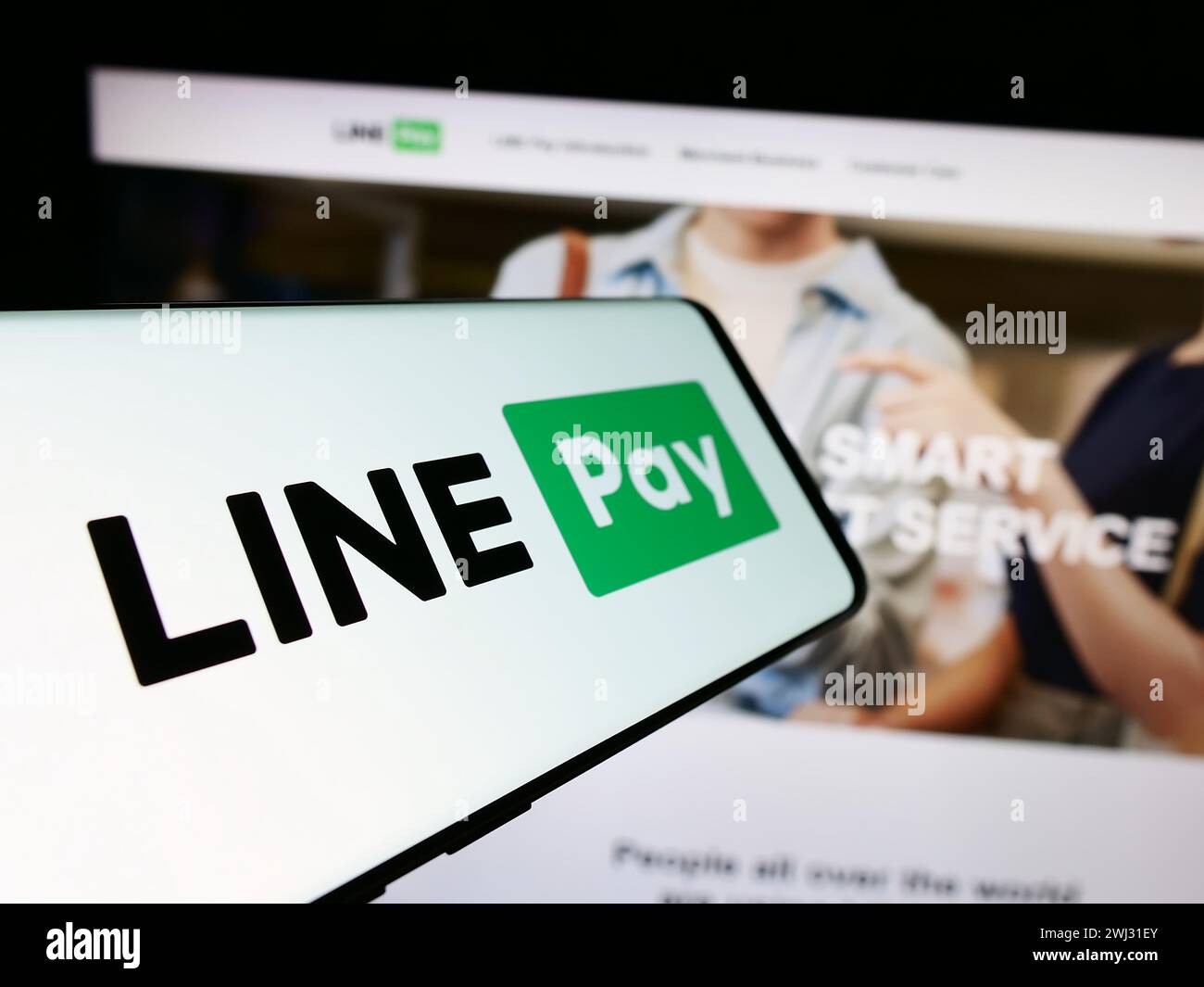 Telefono cellulare con logo della società di pagamenti tailandese LINE pay davanti al sito web aziendale. Mettere a fuoco la parte centrale sinistra del display del telefono. Foto Stock