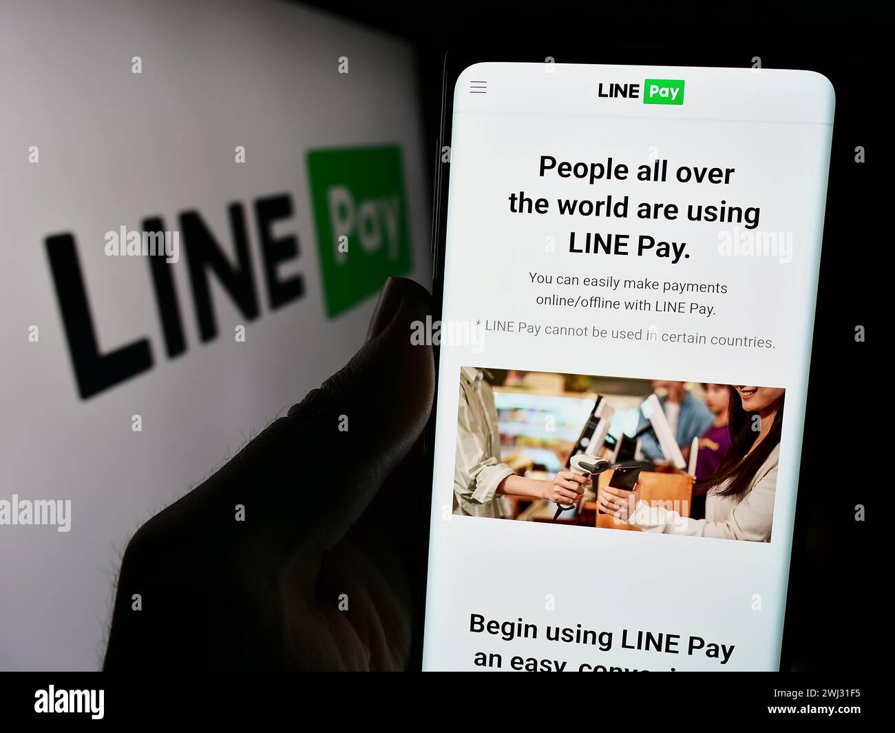 Persona che detiene un cellulare con pagina web della società thailandese DI pagamento LINEA paga davanti al logo aziendale. Messa a fuoco al centro del display del telefono. Foto Stock