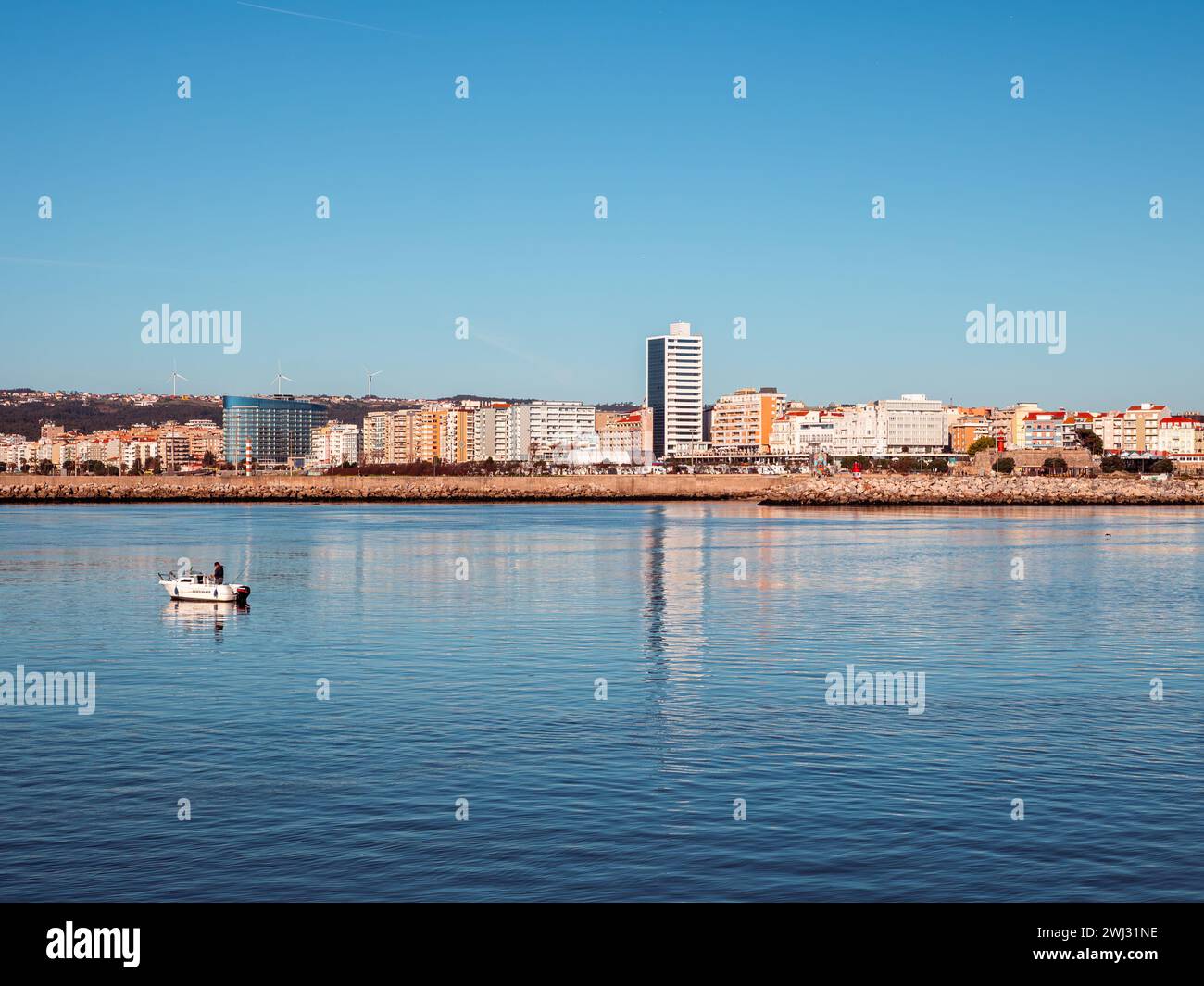Figueira da Foz, Portogallo - 20 gennaio 2024: Vista frontale del centro città con una piccola barca da pesca galleggiante sul fiume Mondego Foto Stock
