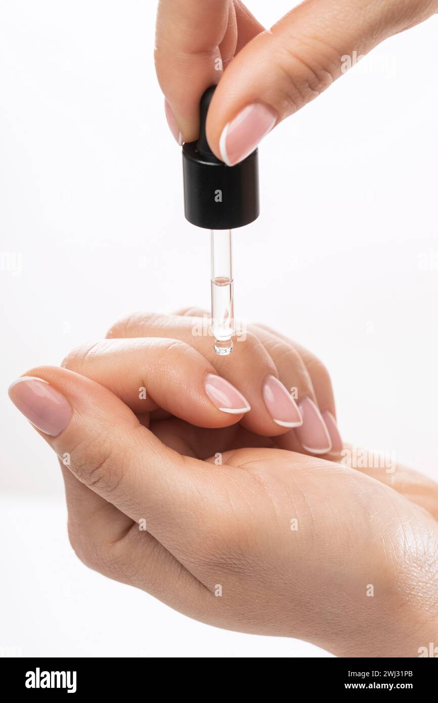 Mani femminili e bottiglia di olio nutriente per cuticola con contagocce Foto Stock