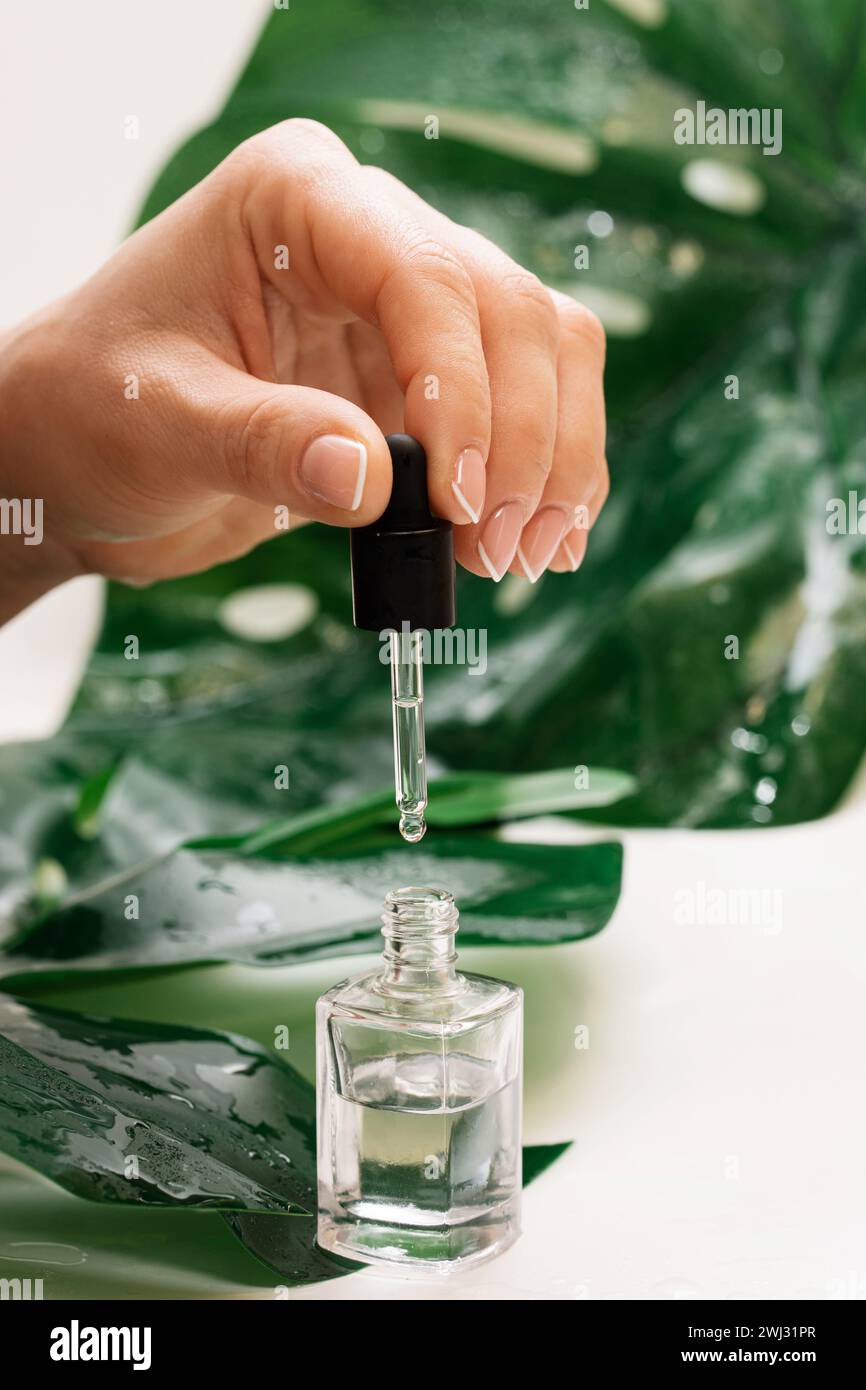Mani femminili e bottiglia di olio nutriente per cuticola con contagocce Foto Stock