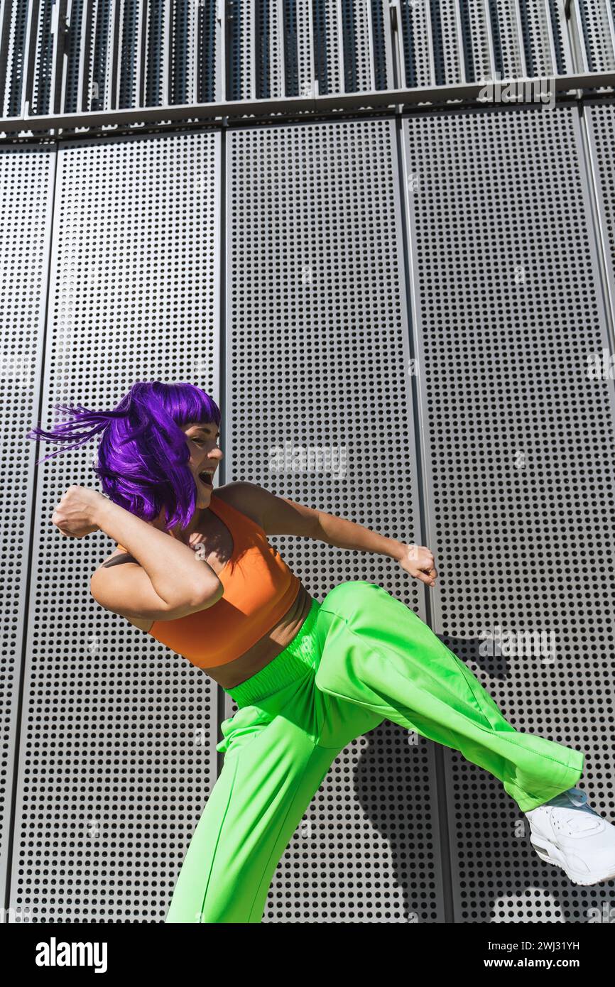 Ballerina spensierata che indossa abbigliamento sportivo colorato e si diverte in strada durante la giornata estiva di sole Foto Stock