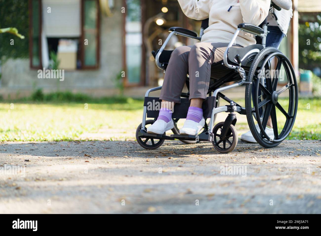 Casa di riposo. Giovane assistente che aiuta le donne anziane in sedia a rotelle Foto Stock
