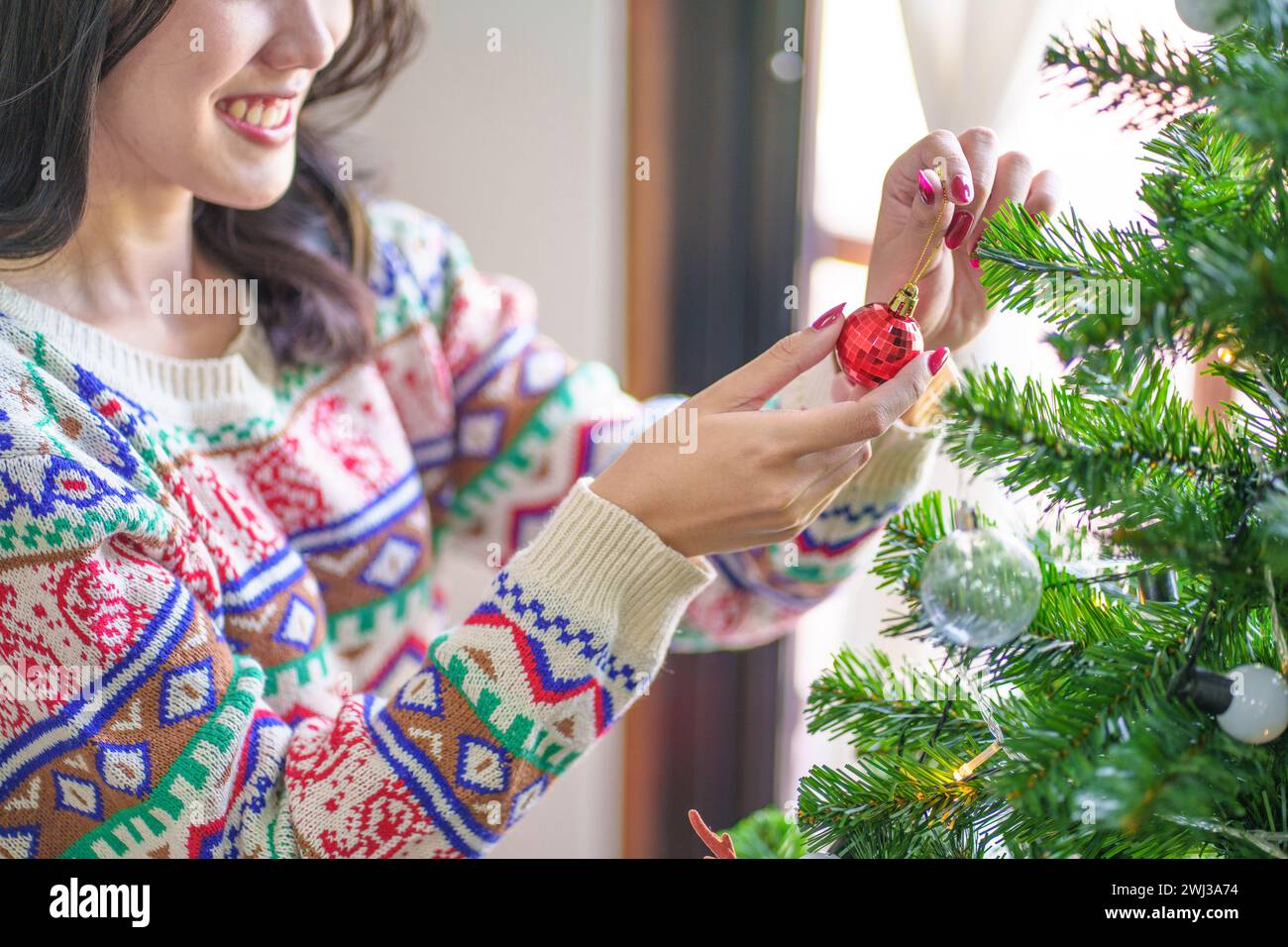 Felice donna asiatica che decora l'albero di Natale per le vacanze di Natale Foto Stock