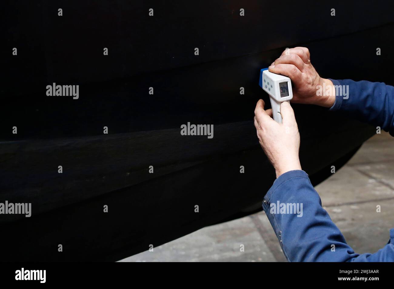 Un tecnico addetto alla manutenzione che misura lo spessore dello scafo in acciaio di un'imbarcazione utilizzando un dispositivo a ultrasuoni Foto Stock