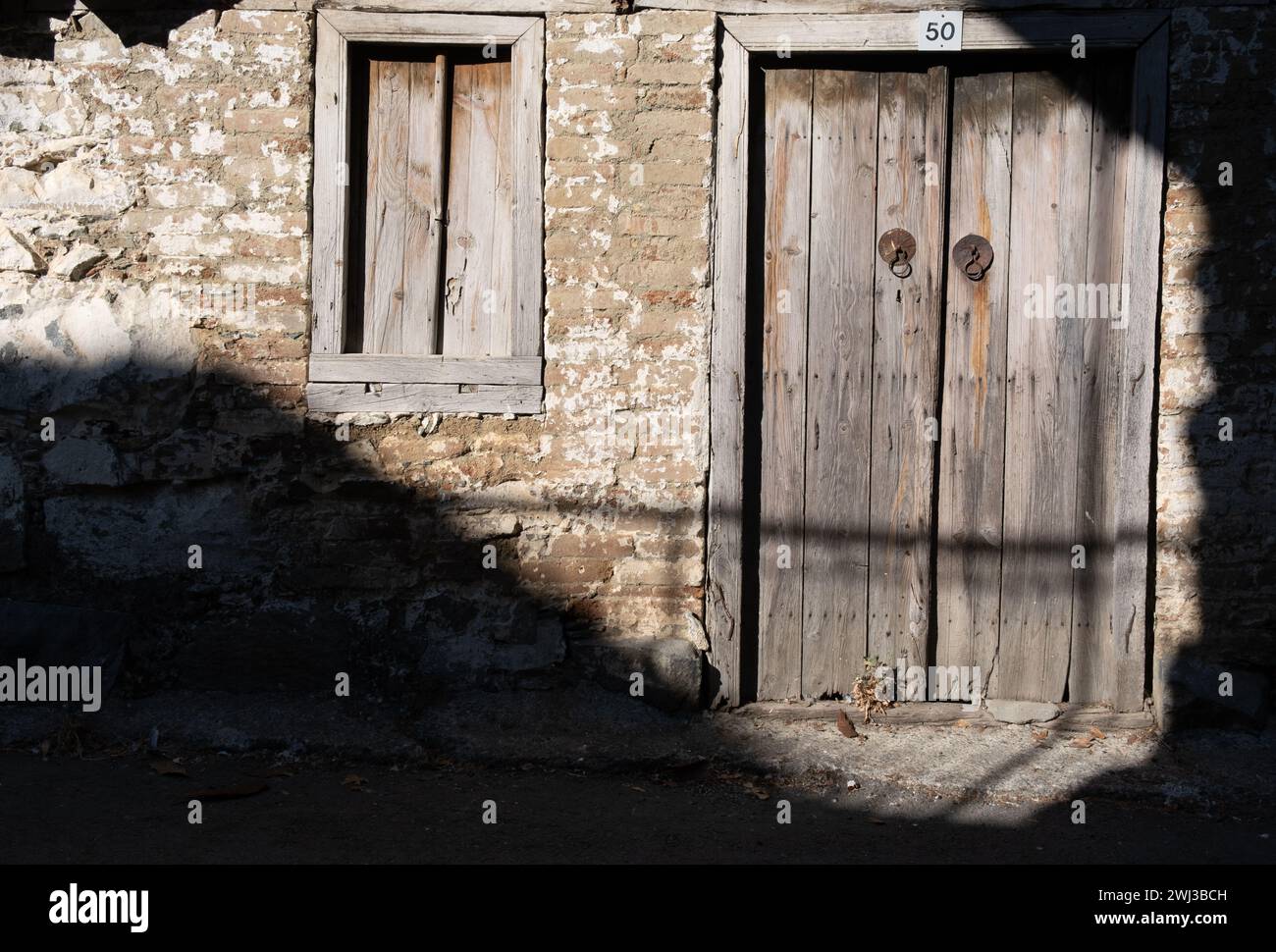 Porta chiusa in legno danneggiata. Porte tradizionali di cipro e muro di mattoni. Luoghi deserti Foto Stock