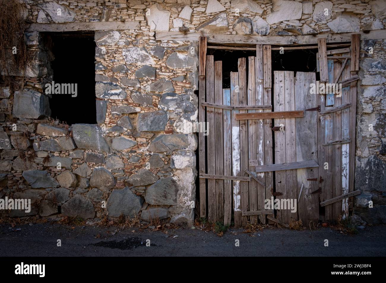 Porta chiusa in legno danneggiata. Porte tradizionali di cipro e muro di mattoni. Luoghi deserti Foto Stock