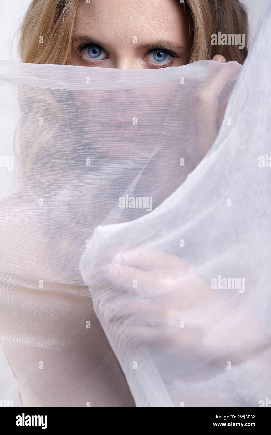 Ritratto di una giovane donna su uno sfondo di tessuto bianco. Concetto di bellezza femminile. Foto Stock