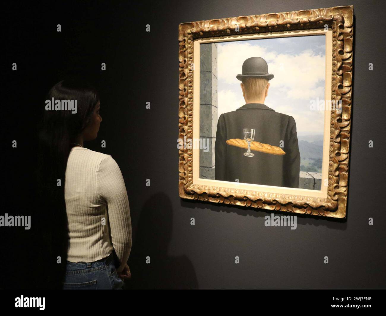 New York, New York, Stati Uniti. 12 febbraio 2024. Una donna vede ''˜l'ami intime' (l'amico intimo) dell'artista René Magritte, dipinto tra gennaio e febbraio 1958, visto in mostra al Christie's Rockefeller Center, come parte del London Highlights ''˜The Art of the Surreal Evening sale'. L'alta stima per cui si prevede che il dipinto venderà è di 50 milioni di dollari - 63 milioni di dollari. (Credit Image: © Nancy Kaszerman/ZUMA Press Wire) SOLO PER USO EDITORIALE! Non per USO commerciale! Foto Stock
