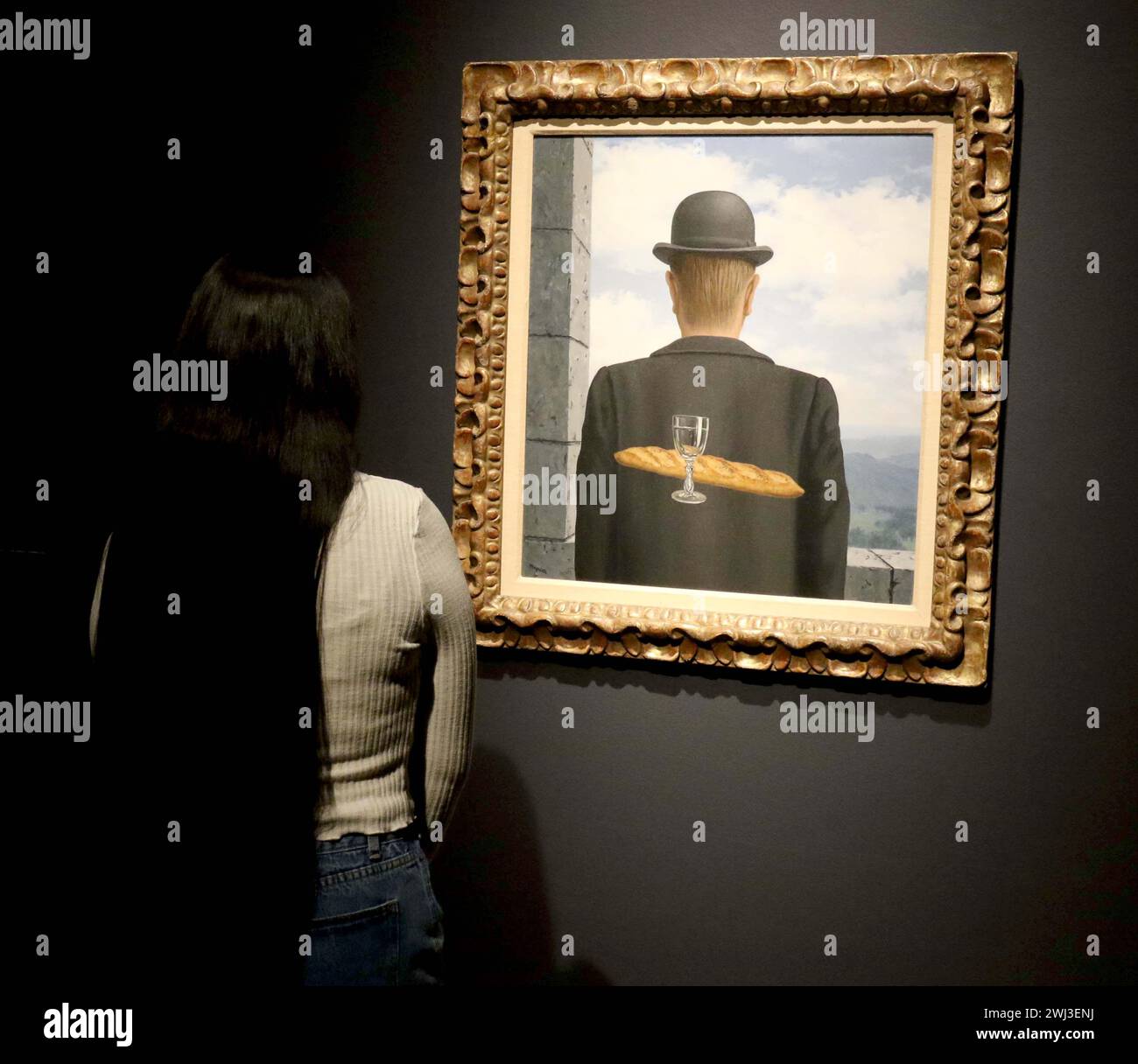 New York, New York, Stati Uniti. 12 febbraio 2024. Una donna vede ''˜l'ami intime' (l'amico intimo) dell'artista René Magritte, dipinto tra gennaio e febbraio 1958, visto in mostra al Christie's Rockefeller Center, come parte del London Highlights ''˜The Art of the Surreal Evening sale'. L'alta stima per cui si prevede che il dipinto venderà è di 50 milioni di dollari - 63 milioni di dollari. (Credit Image: © Nancy Kaszerman/ZUMA Press Wire) SOLO PER USO EDITORIALE! Non per USO commerciale! Foto Stock