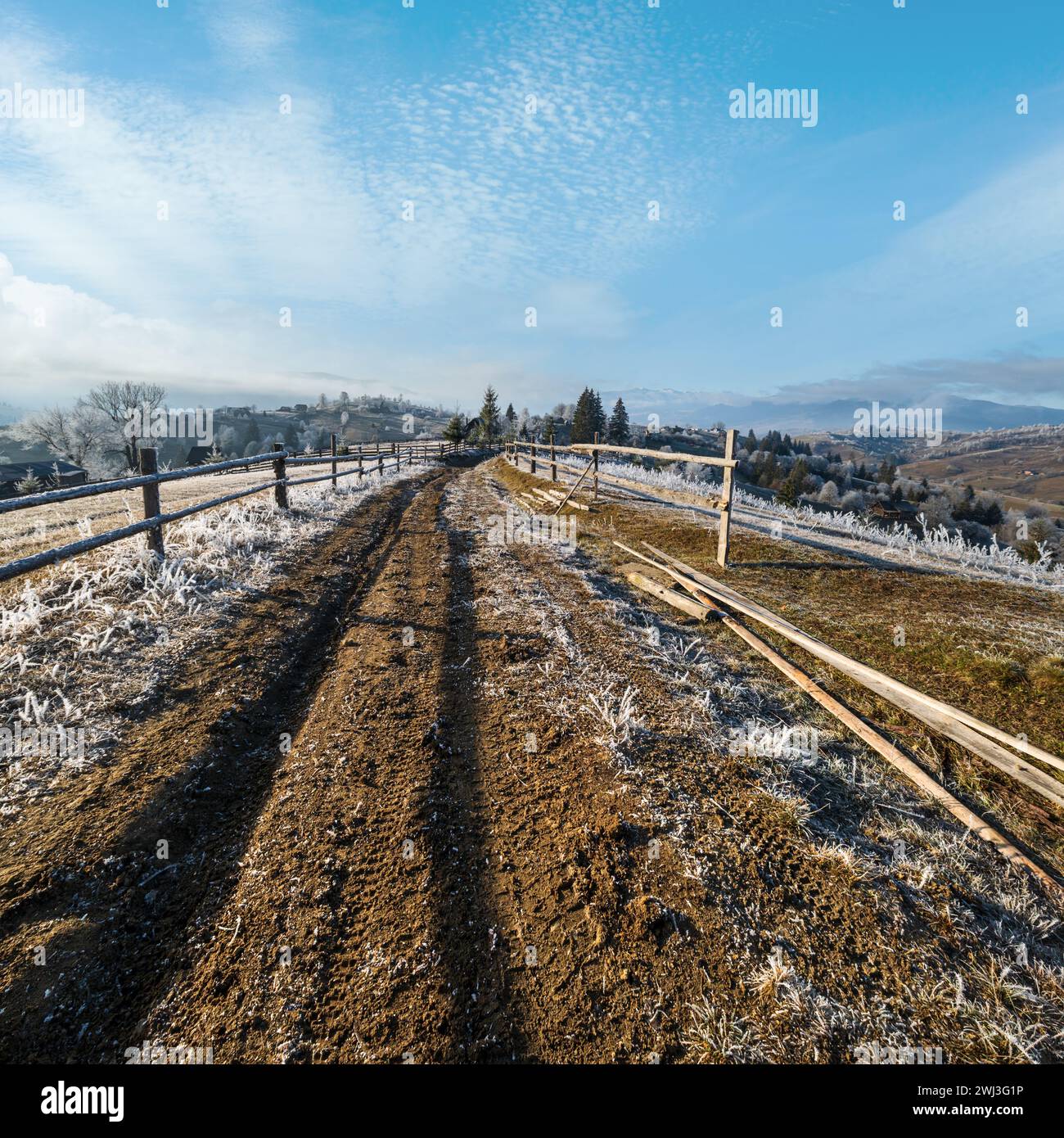 Inverno in arrivo. Ultimi giorni di autunno, mattina in campagna di montagna tranquilla e pittoresca scena hoarfrosted. Strada sporca dalla collina Foto Stock