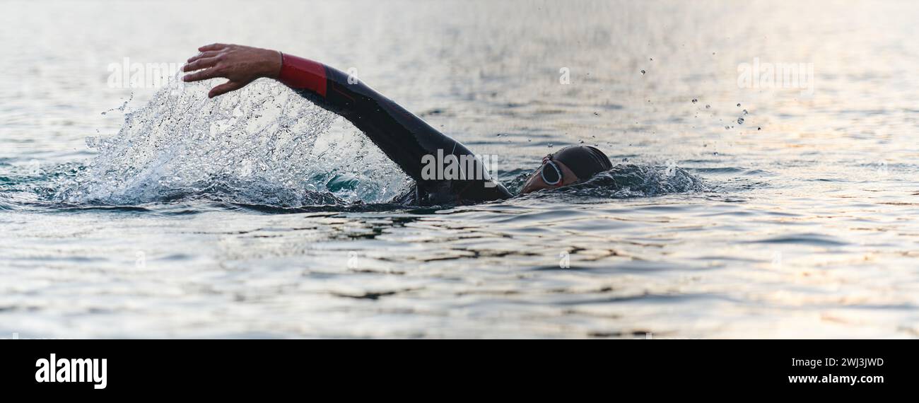 Un triatleta professionista si allena con una dedizione costante per una prossima gara in un lago, emanando un senso di atletica Foto Stock