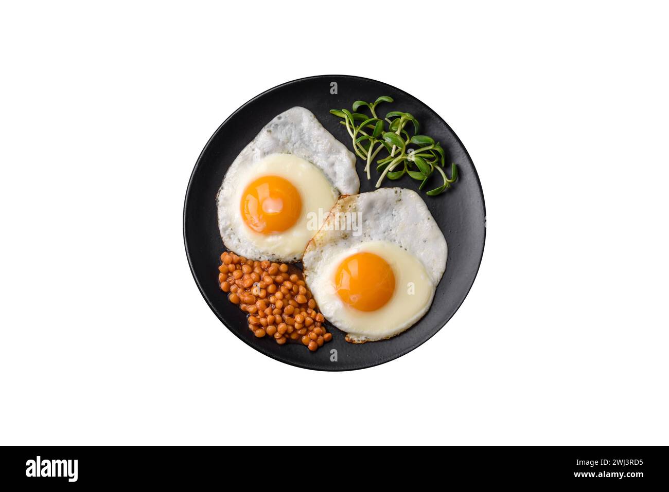 Colazione deliziosa e abbondante, composta da due uova fritte, lenticchie in scatola e microgreen Foto Stock