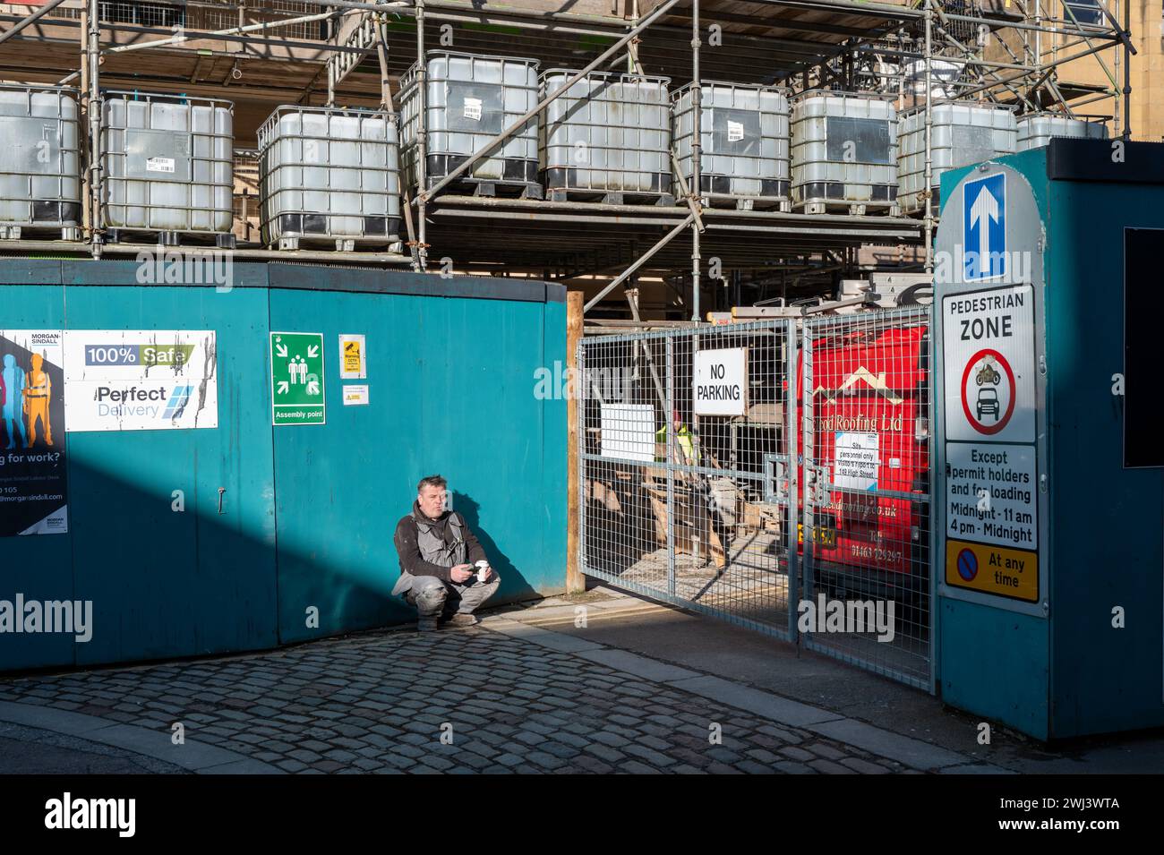 12 febbraio 2024. High Street, Elgin, Moray, Scozia. Si tratta di un operaio edile che beve una tazza di caffè nel cantiere. Foto Stock