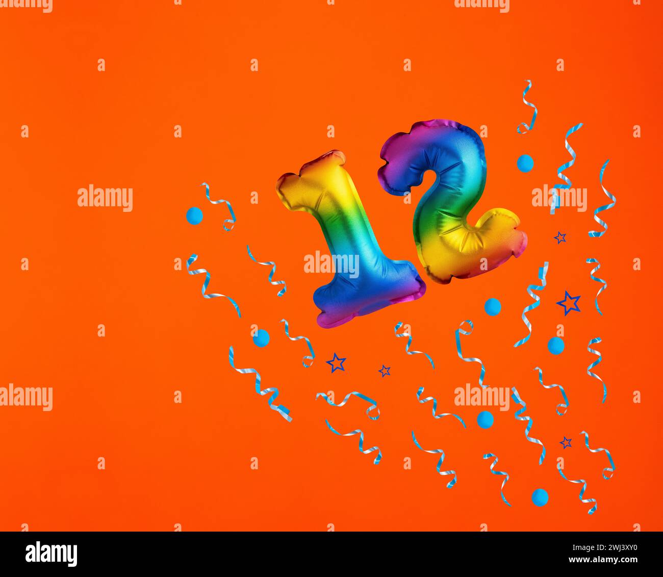 Palloncino multicolore numero 12 - esplosione Confetti su sfondo arancione. Biglietto di compleanno Foto Stock