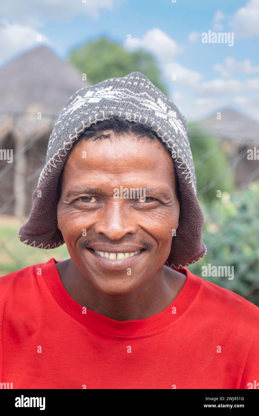 Ritratto di un uomo africano nel villaggio, san african man, trasferito dal Kalahari in nuovi villaggi, con indosso un berretto, Foto Stock