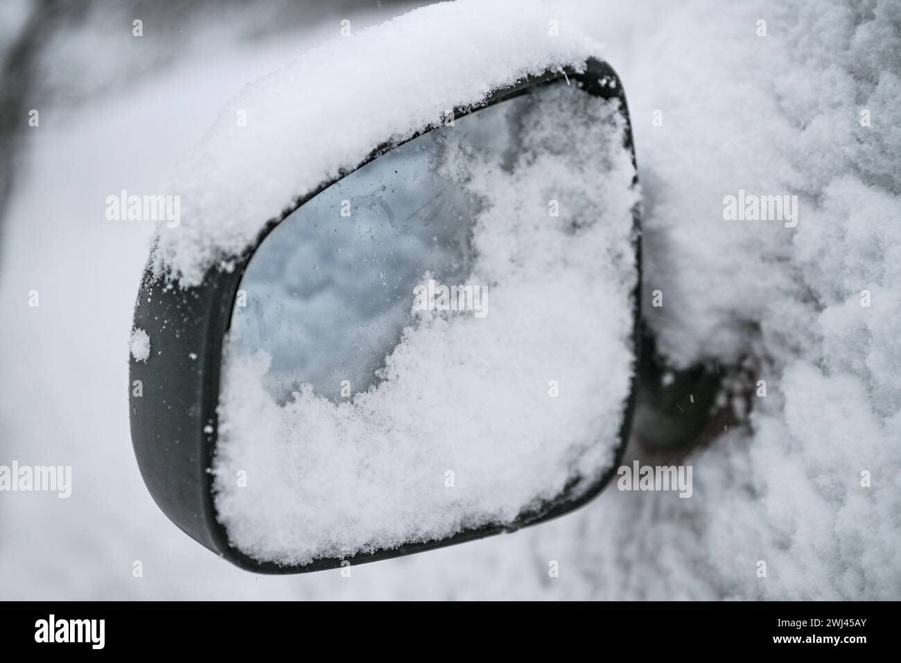 Specchio laterale coperto di neve di un'auto, guida pericolosa in inverno, spazio per copiare, messa a fuoco selezionata Foto Stock
