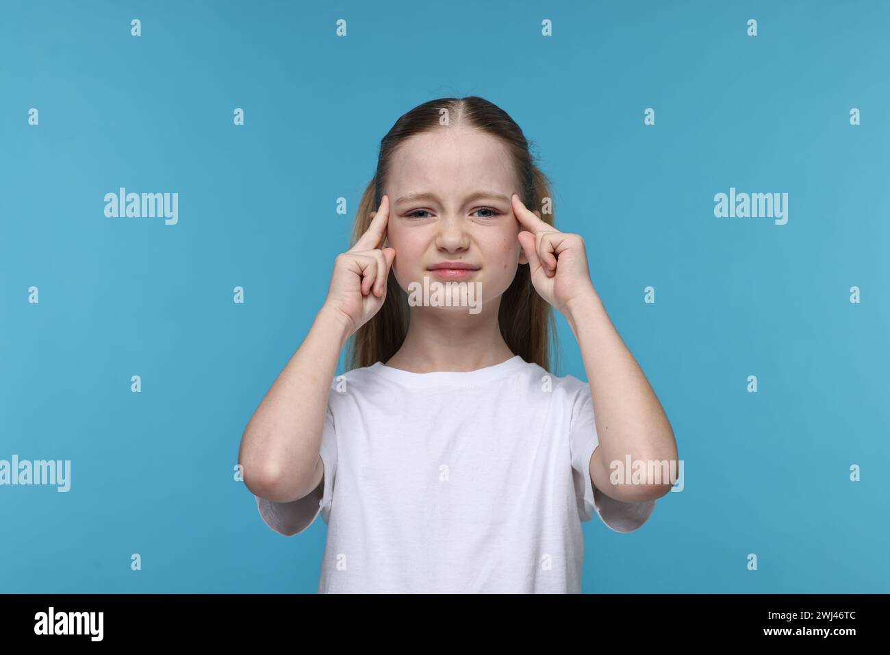 Bambina che soffre di mal di testa su sfondo azzurro Foto Stock