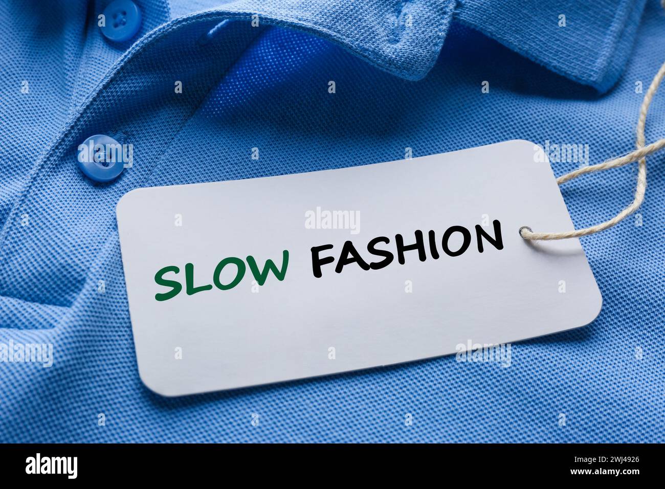Consumo consapevole. Tagga con le parole Slow Fashion su camicia blu e primo piano Foto Stock