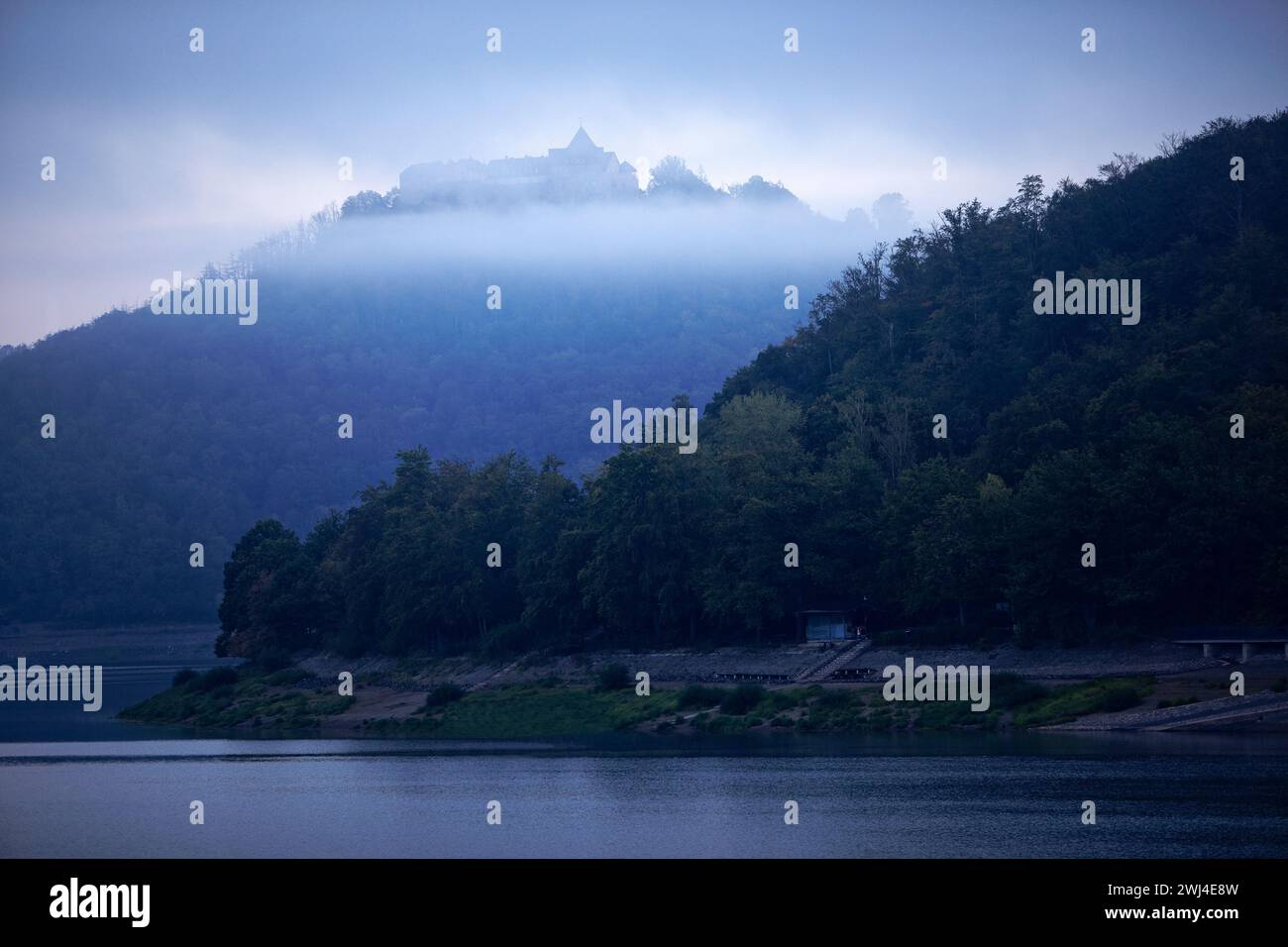 Edersee con vista sul castello in cima alla collina, il castello di Waldeck nella nebbia mattutina, Edertal, Germania Foto Stock