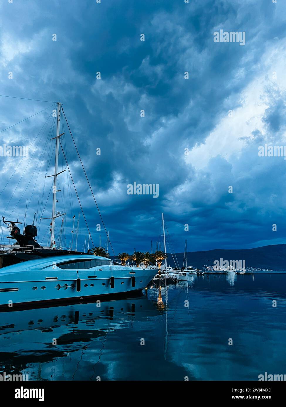 Uno yacht a motore bianco sorge sul molo sullo sfondo di un cielo scuro al crepuscolo Foto Stock