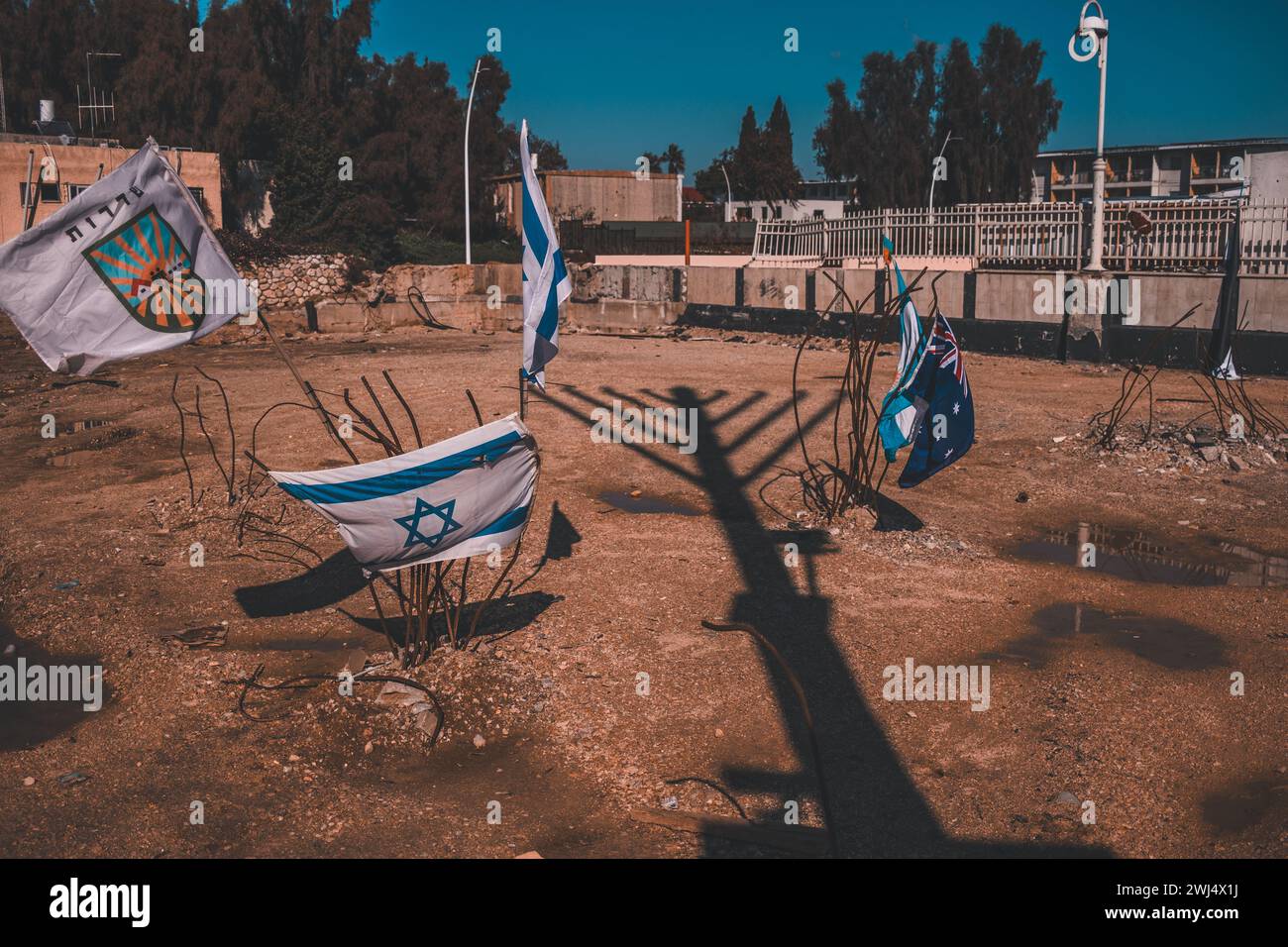 Piccolo gruppo di bandiere israeliane su una superficie desolata, accompagnate da varie bandiere e individui Foto Stock
