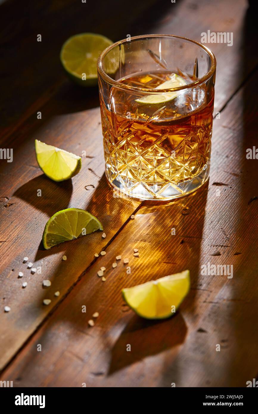 Bevanda estiva, whisky, tequila o cognac, limonata, cocktail alcolico o analcolico con limes e sale su un tavolo di legno Foto Stock