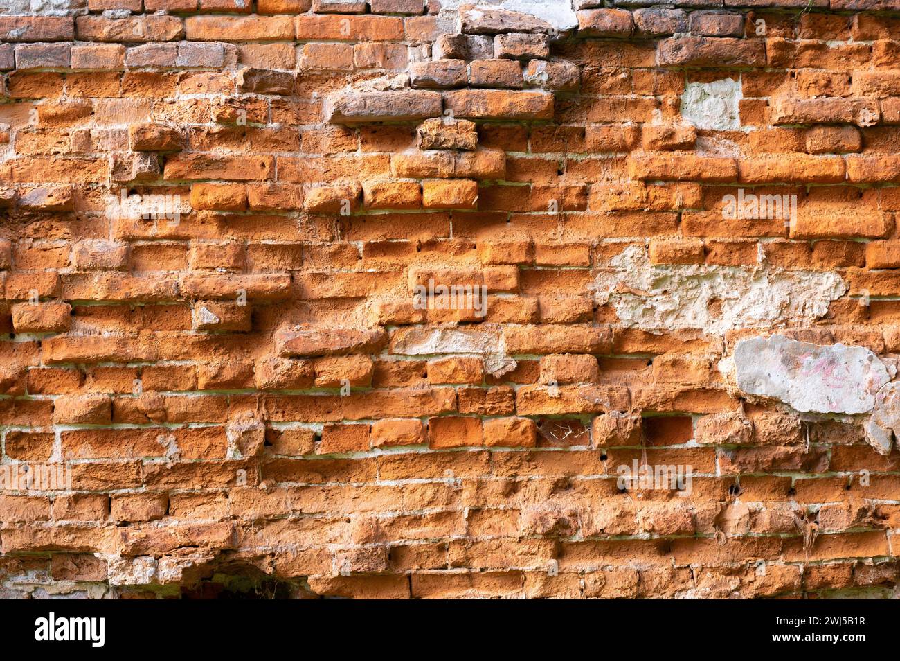 Un vecchio muro di mattoni con mattoni che si stanno deteriorando molto dal tempo e influenze esterne Foto Stock