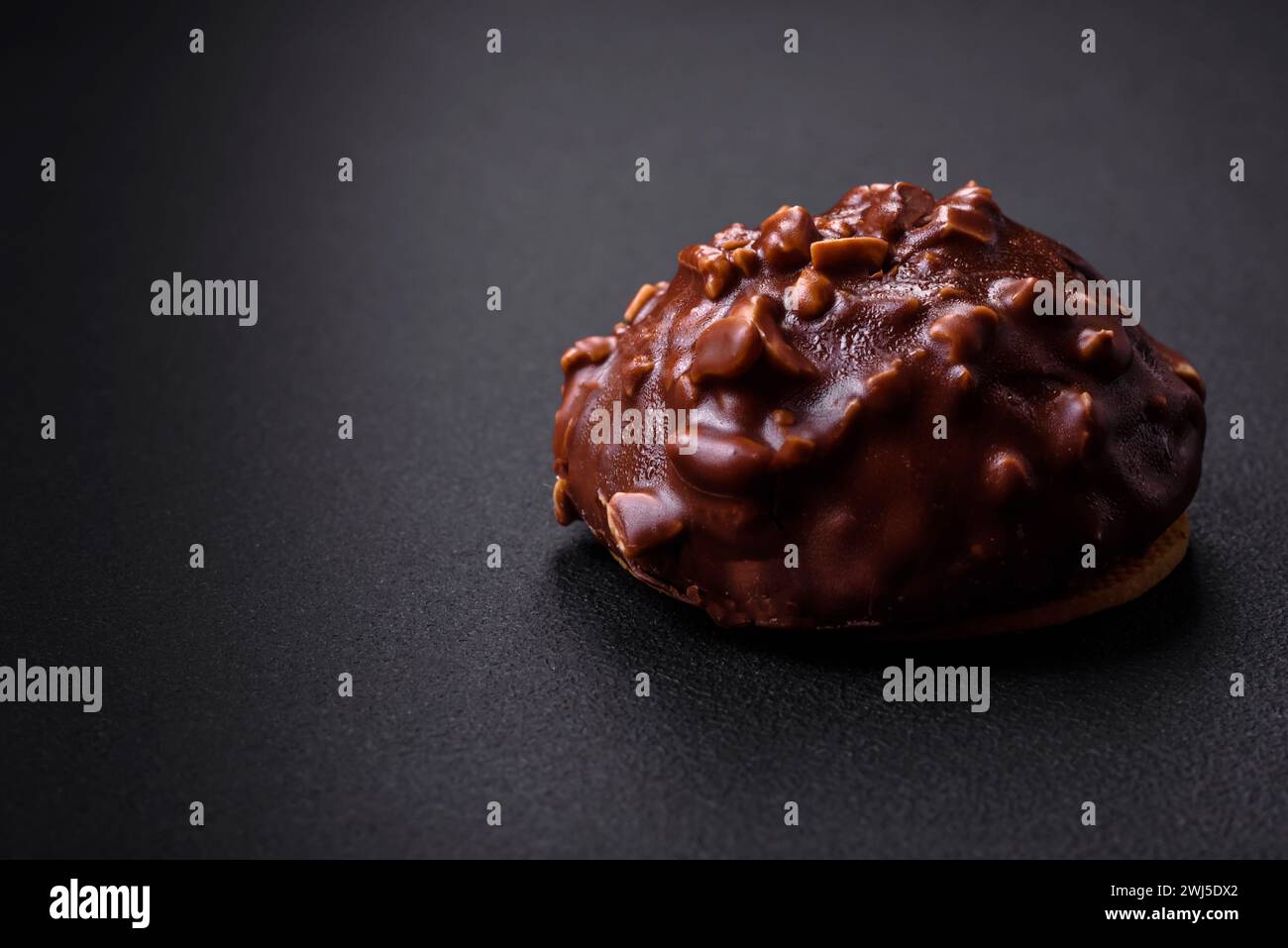 Deliziosa crostata di cioccolato con noci su un piatto di ceramica nera su fondo di cemento scuro Foto Stock