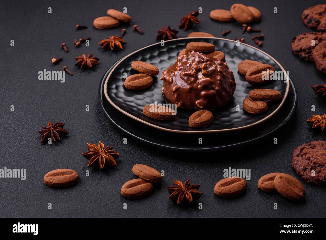 Deliziosa crostata di cioccolato con noci su un piatto di ceramica nera su fondo di cemento scuro Foto Stock