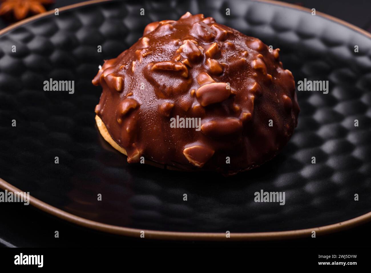 Deliziosa crostata di cioccolato con noci su un piatto di ceramica nera su fondo di cemento scuro Foto Stock