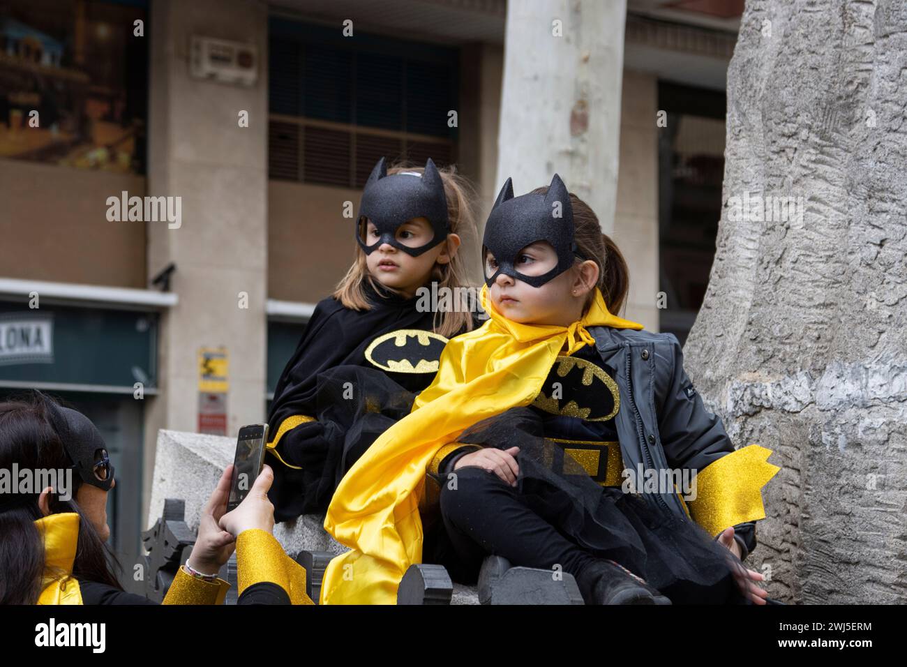 Due bambini in costume Batman e Batgirl durante il carnevale di Barcellona, Spagna. Foto Stock